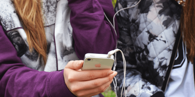 Jongere gebruikt smartphone met oordopjes.