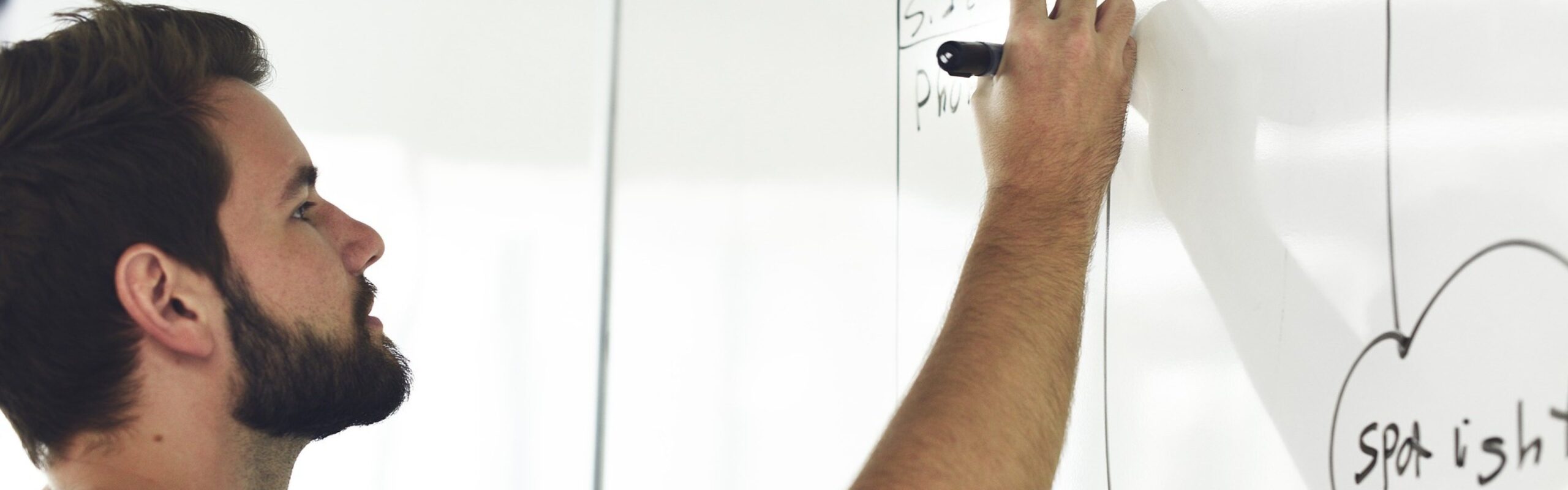 Man schrijft op een whiteboard tijdens een brainstormsessie.