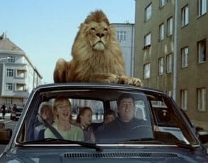 advertentie Apeldoorn, waarbij er een gezin in de auto zit met een leeuw op het dak.