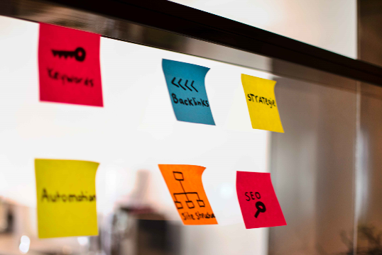 Brainstormsessie voor SEO contentstrategie met post-its op een glazen wand.