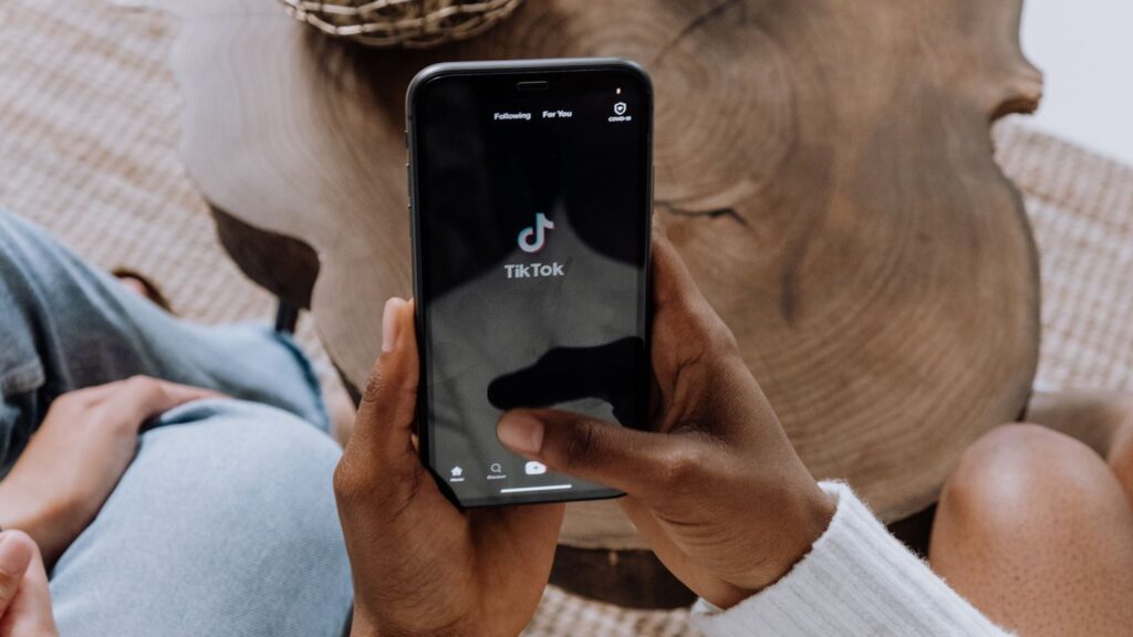 Smartphone met TikTok app in handen van gebruiker die door korte video’s op sociale media scrolt.