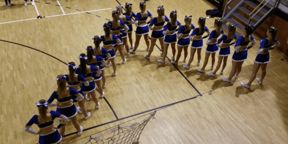 Cheerleaders staand in een v vorm.